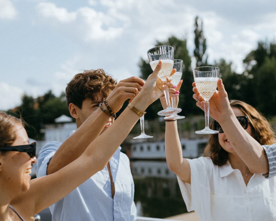 Group toasting champagne on a yacht deck under a blue Miami sky